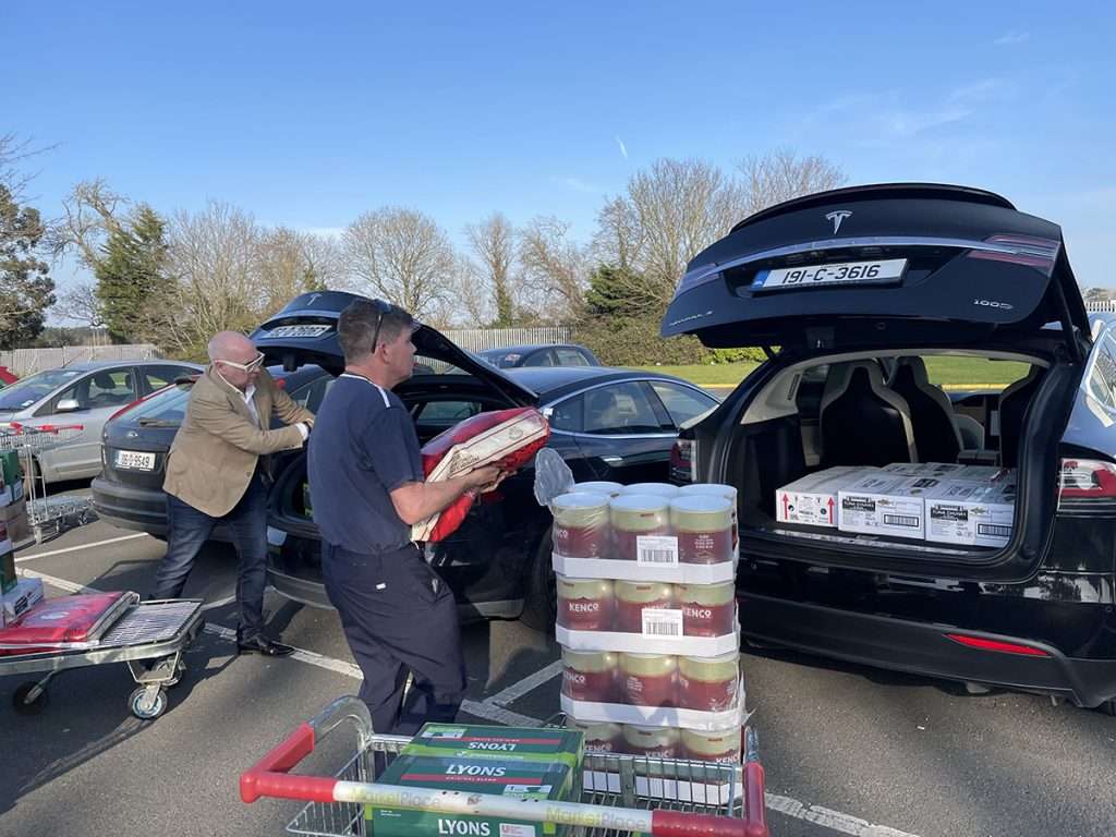 two members of the Tesla convoy putting supplies in their boots for ukrainian refugees in September 2022